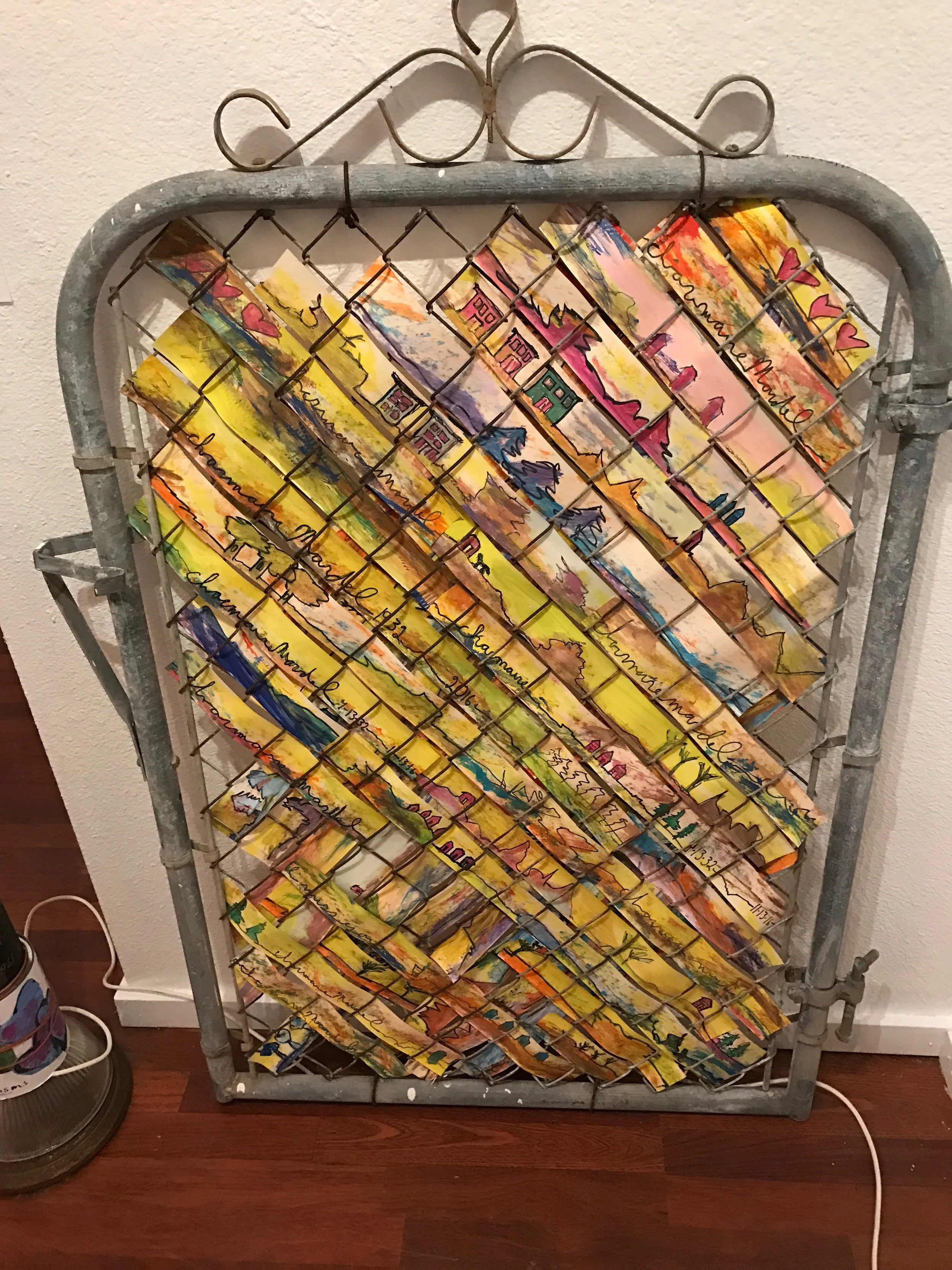 Vintage metal gate is woven with tempera on paper with landscape scenes and family mementos