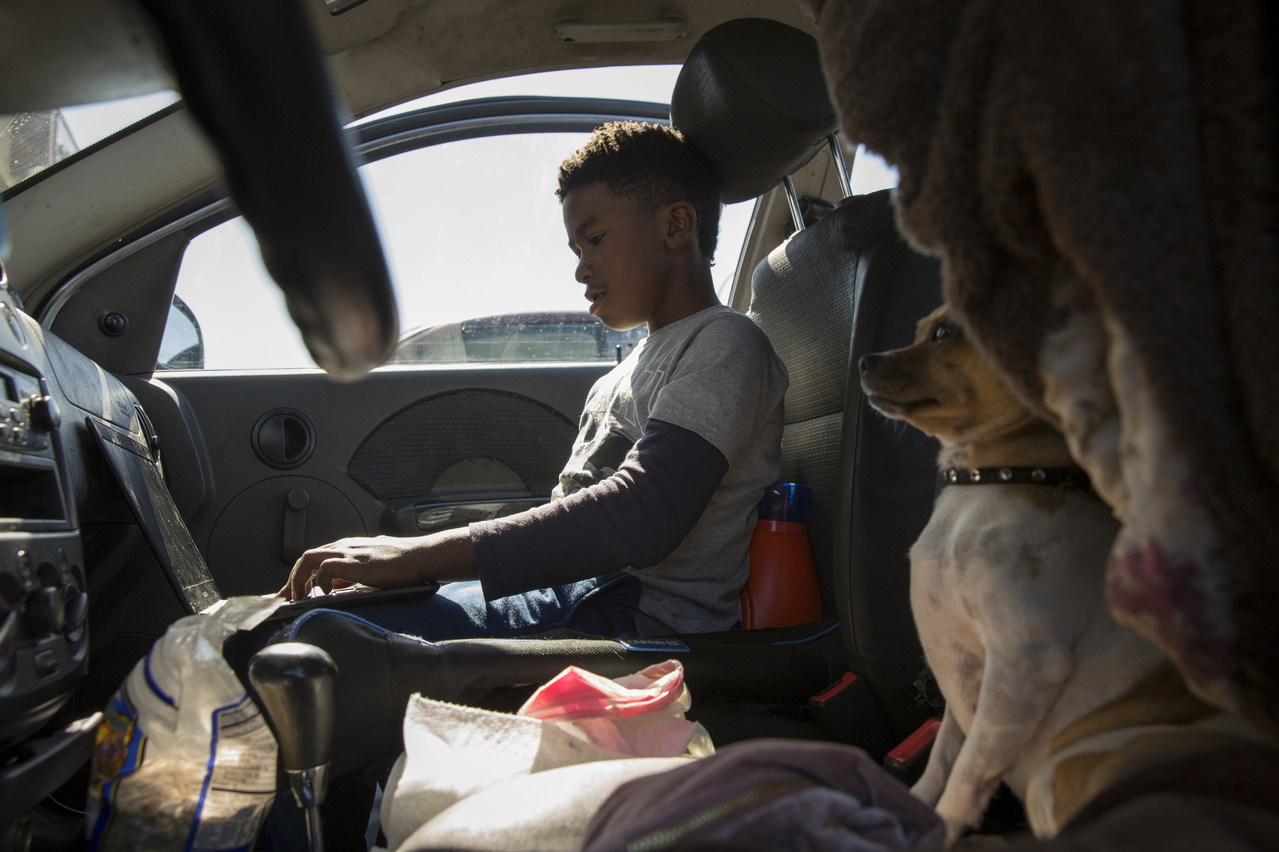  David Johnson plays video games in a sedan with his dog Tinker Bell sitting next to him in Richmond, Calif., on Saturday, Oct. 13, 2018. Johnson used to live in this car with his mother, sister and Tinker Bell. 