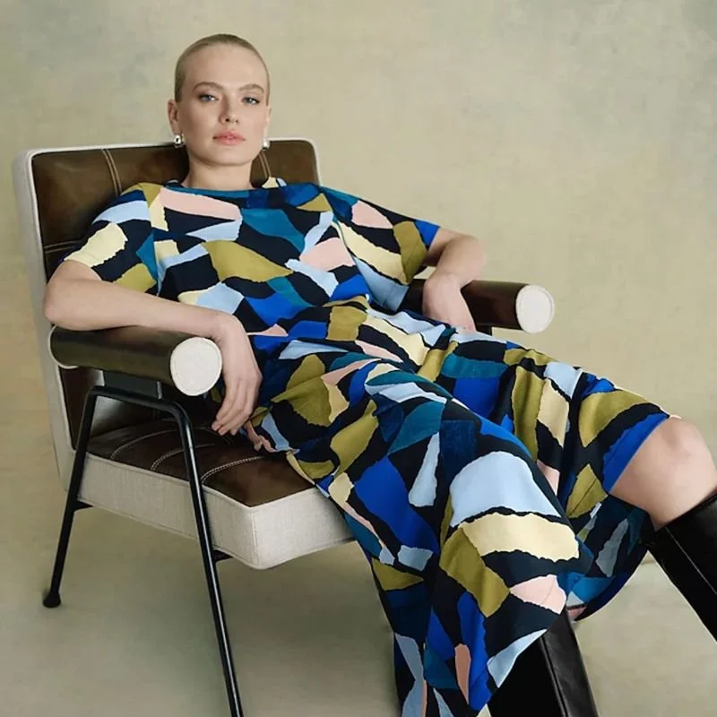 Seated woman wearing patterned dress designed by Emma Townsend