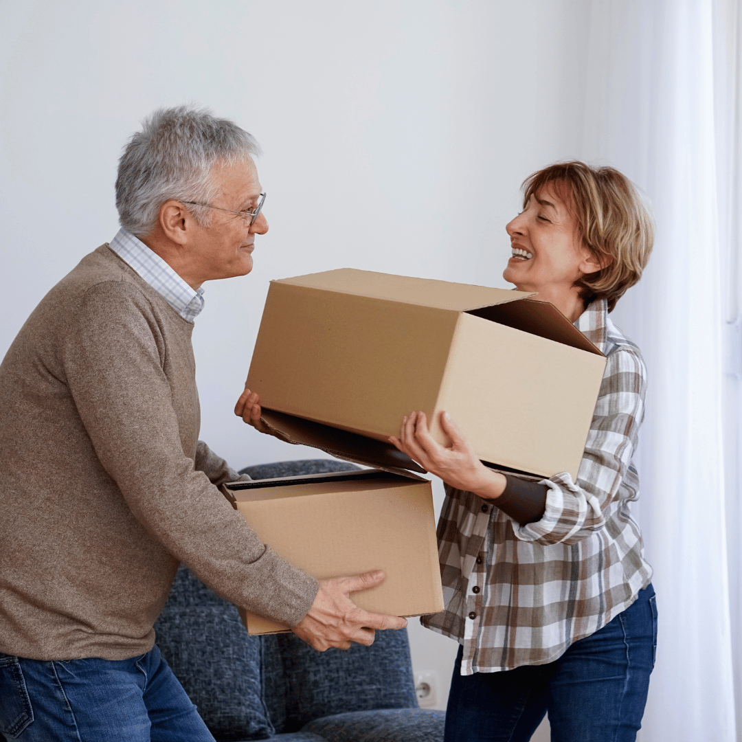A woman giving a cardboard box to a man in a living room.