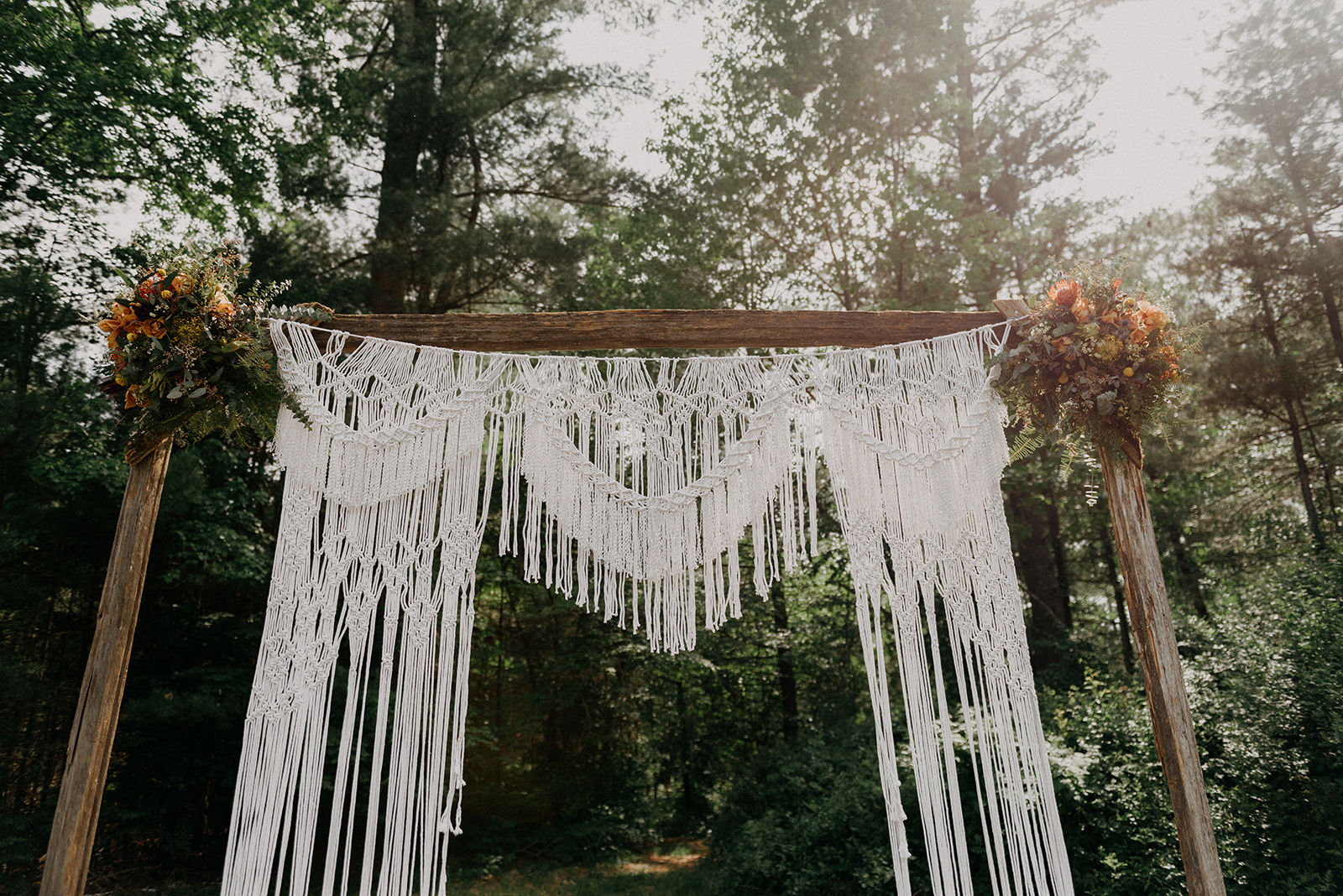 Macrame back drop with wooden arch for a wedding ceremony at an outdoor wedding on an antique farm - Pearl Weddings & Events