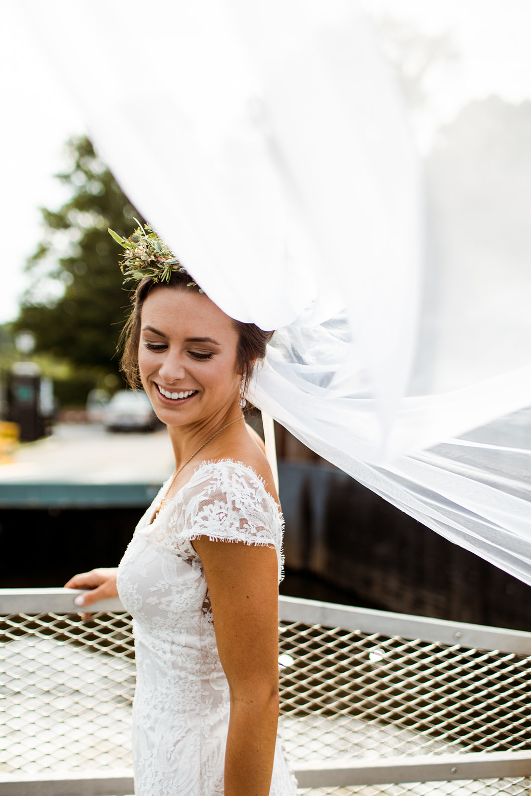 Bride with her blowing veil and beautiful floral crown by the water in Chester, CT - Pearl Weddings & Events