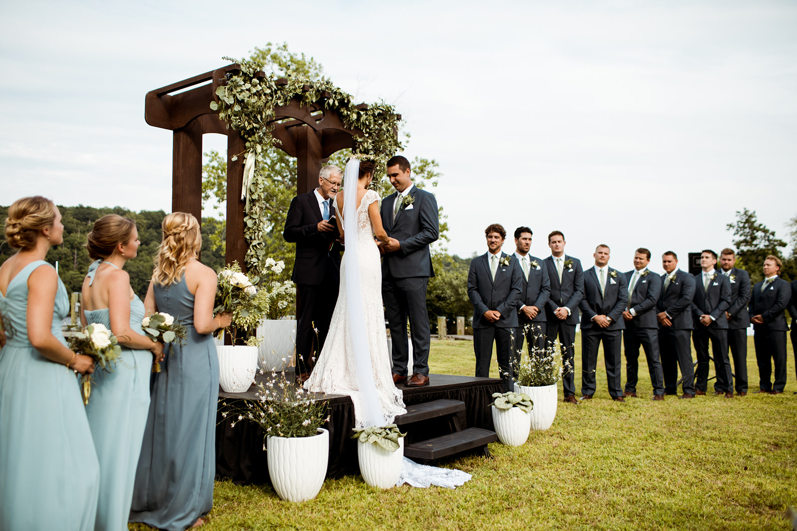 Sommar & Ben's wedding by the water in Connecticut. Wooden wedding arch way and white potted plants for the ceremony decor. - Pearl Weddings & Events