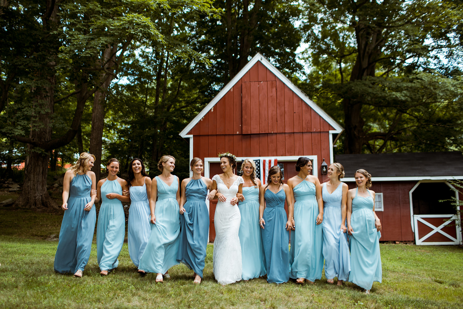 different shades of blue bridesmaid dresses. Bride with a flower crown. Red barn at Tiny Tiffany's farm. Chester, Connecticut outdoor tented wedding. - Pearl Weddings & Events