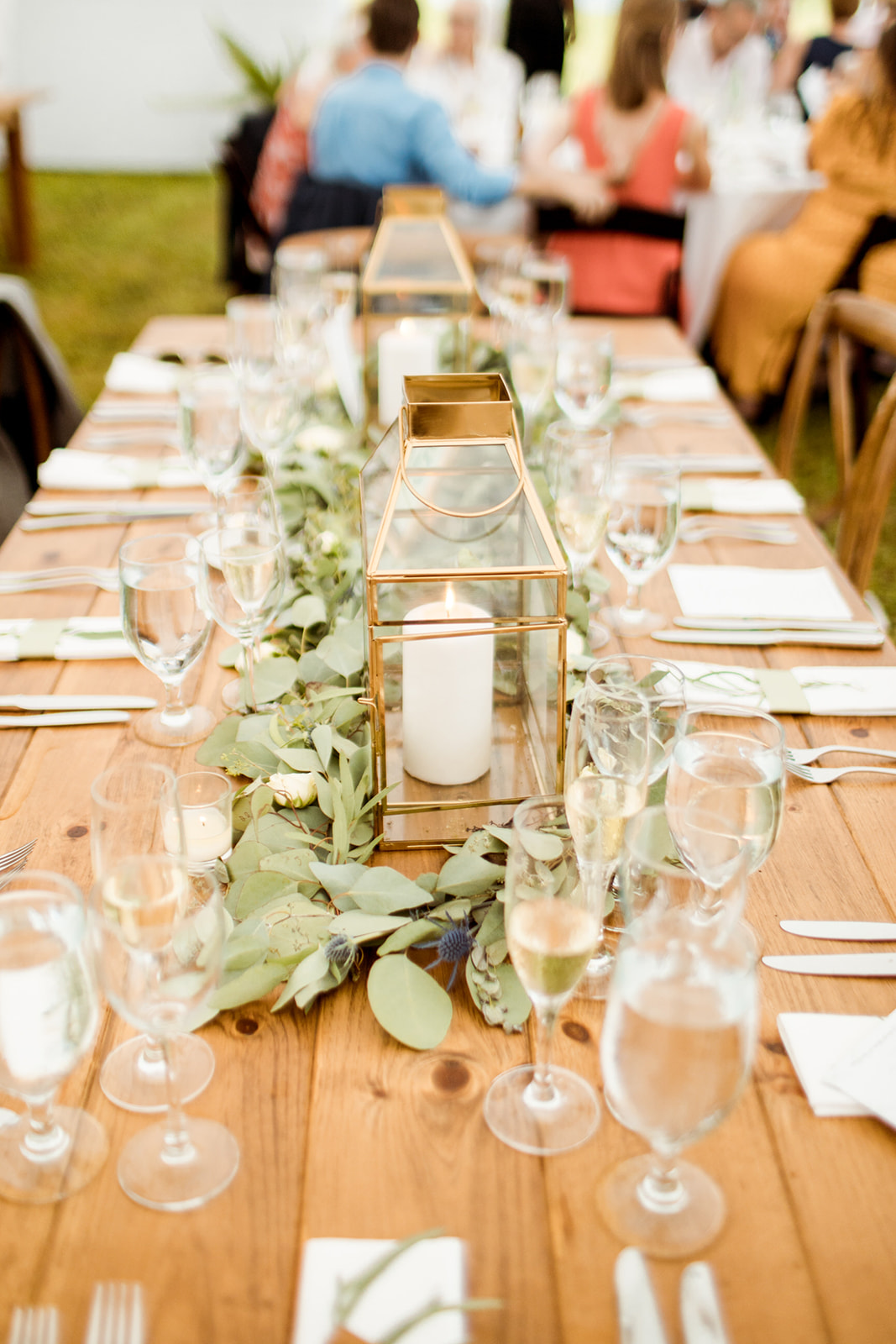 Greenery on farm tables with vintage white napkins and gold candle holders - Pearl Weddings & Events