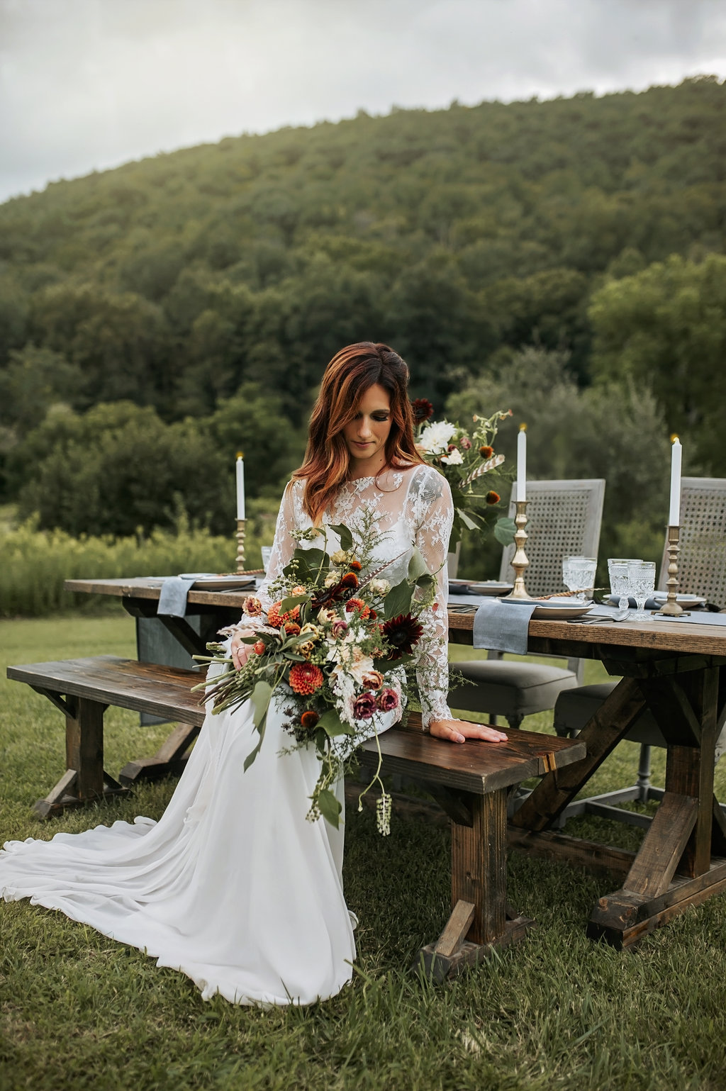 Bride in a two piece wedding dress with a floral bouquet that has feathers in it! -Pearl Weddings & Events