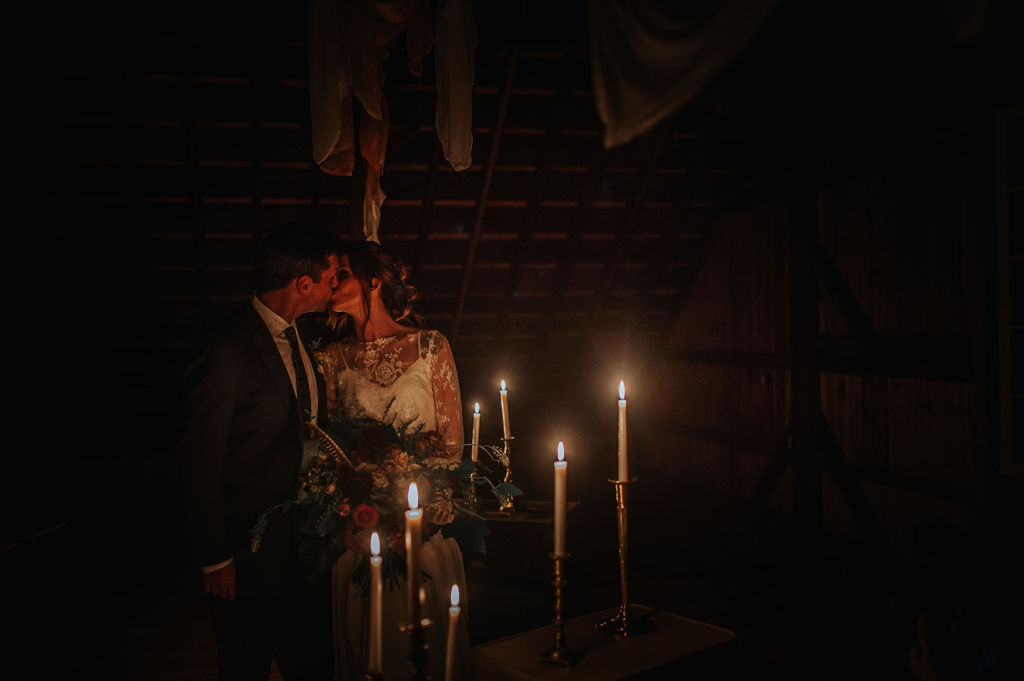 moody candle light kiss after there night time ceremony - Pearl Weddings & Events
