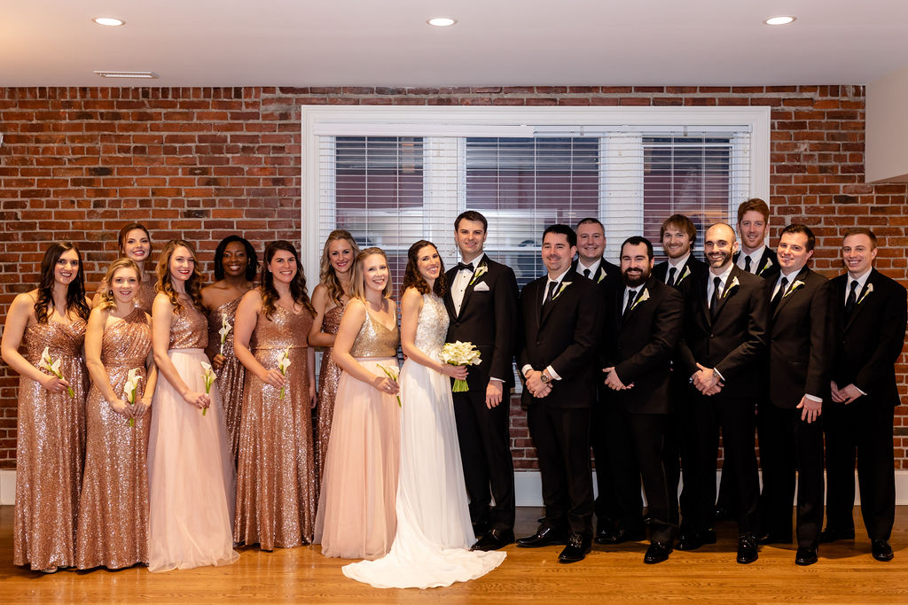 Bride and groom and their wedding party. Groomsmen are in all black and the bridesmaids are in blush pink . - Pearl Weddings & Events