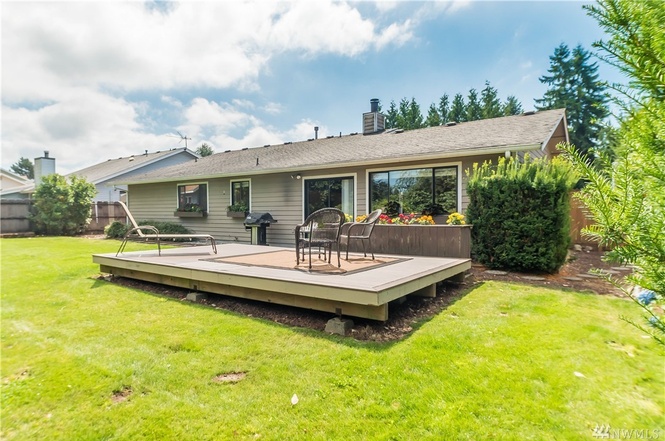 Fully-fenced backyard with deck and a nice lawn.