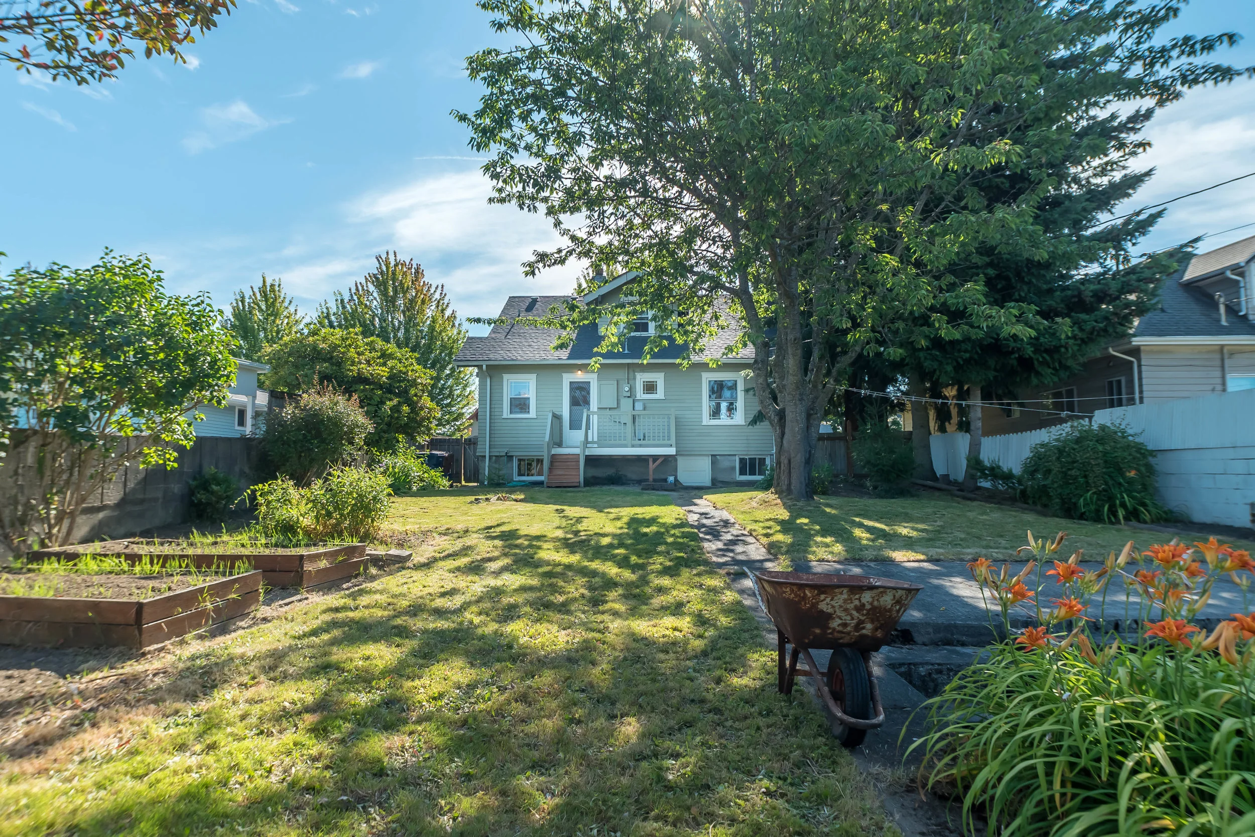 Backyard complete with raised beds, mature shrubs, and trees for a mix of sun and shade. 