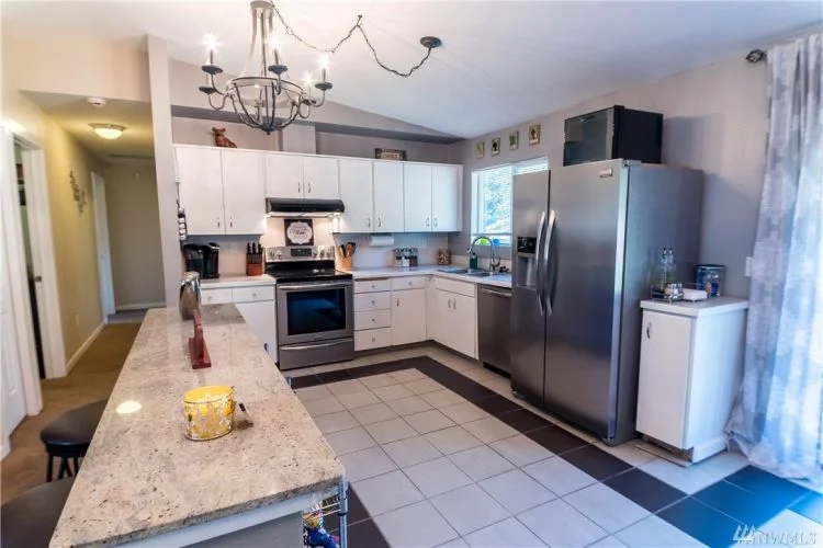A convenient kitchen with bright cupboards, an easy to clean tile floor, and great appliances.