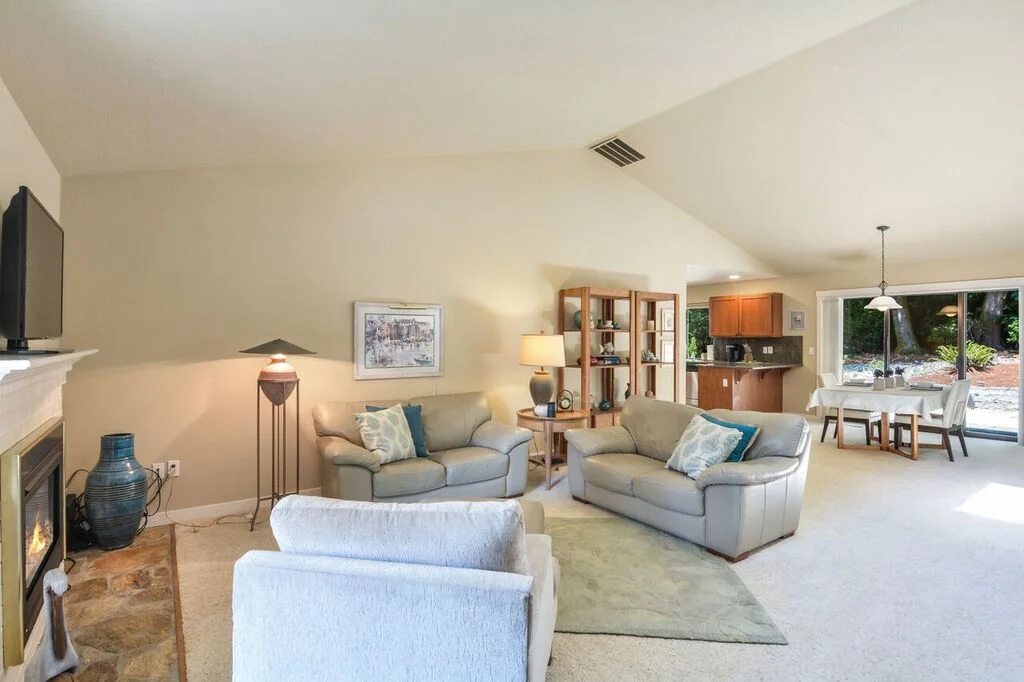 Another view of the high vaulted ceiling over the open floor plan of the living and dining area. The stone hearth extends to the front door.