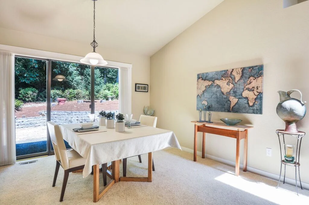 The dining room beneath the vaulted ceiling is bright and open to the kitchen. The triple panel sliding glass door leads to the patio and back yard.