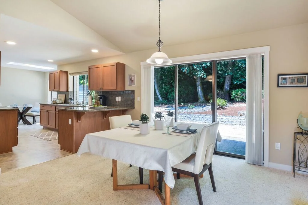 The triple panel sliding glass doors let some of the outside in with a view to the lawn and evergreens beyond.