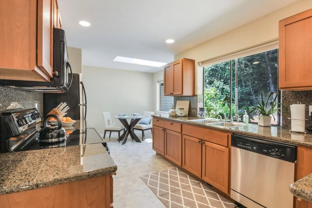 The kitchen is finished with granite tile counters, stainless appliances, a double sink, plenty of window light, a skylight, and a nice bar counter where you could pull up a set of stools.