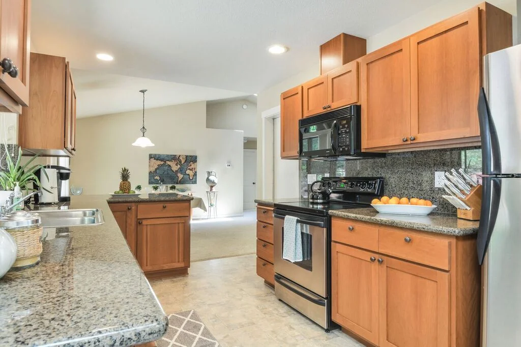 Glass top stove, dishwasher, microwave, refrigerator, plenty of counter space, and garage access (not pictured). Another view of the many cabinets and drawers provided in this well appointed kitchen to help keep you organized.