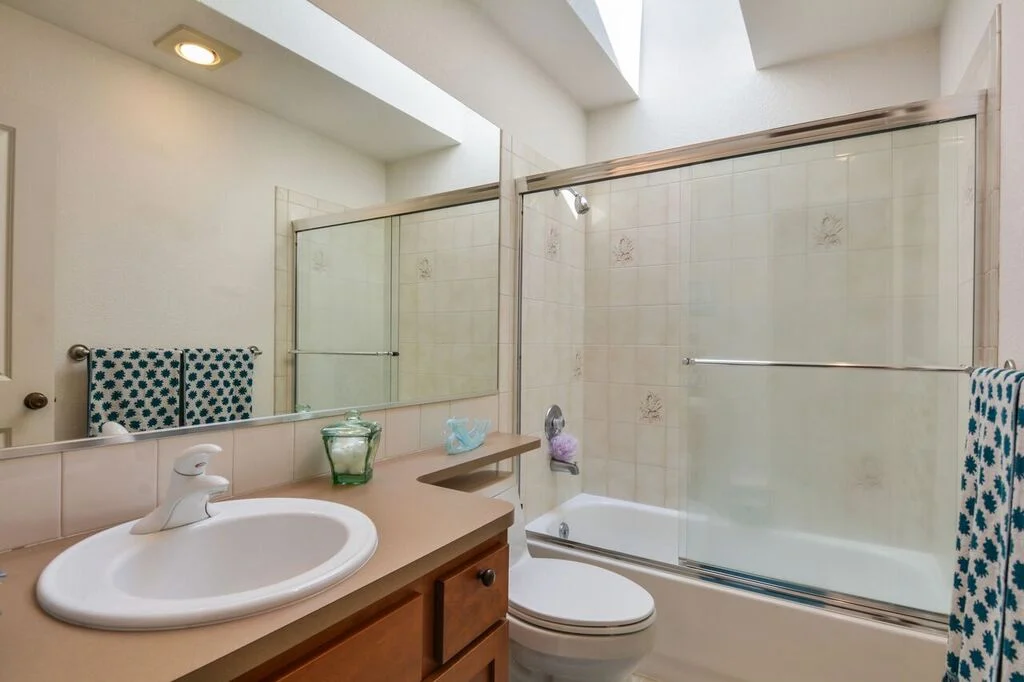 This full bath is accessible from the living room and is next door to the second bedroom. A skylight brings in natural light and the large mirror helps keep things bright.