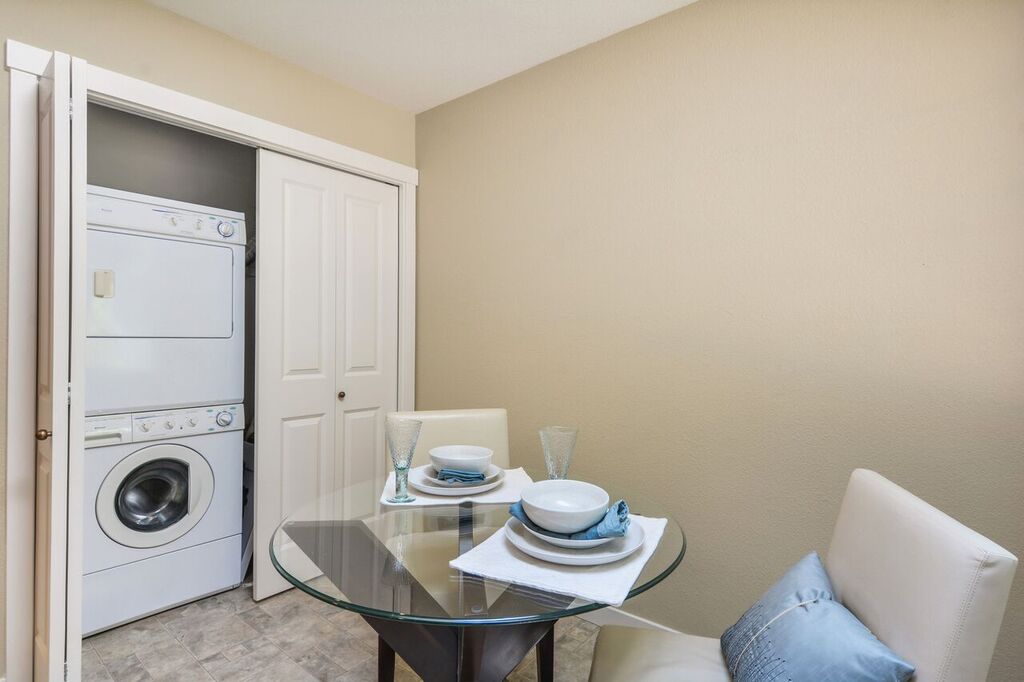 Stacked washer and dryer conveniently located off the kitchen with pantry shelves behind the other door.