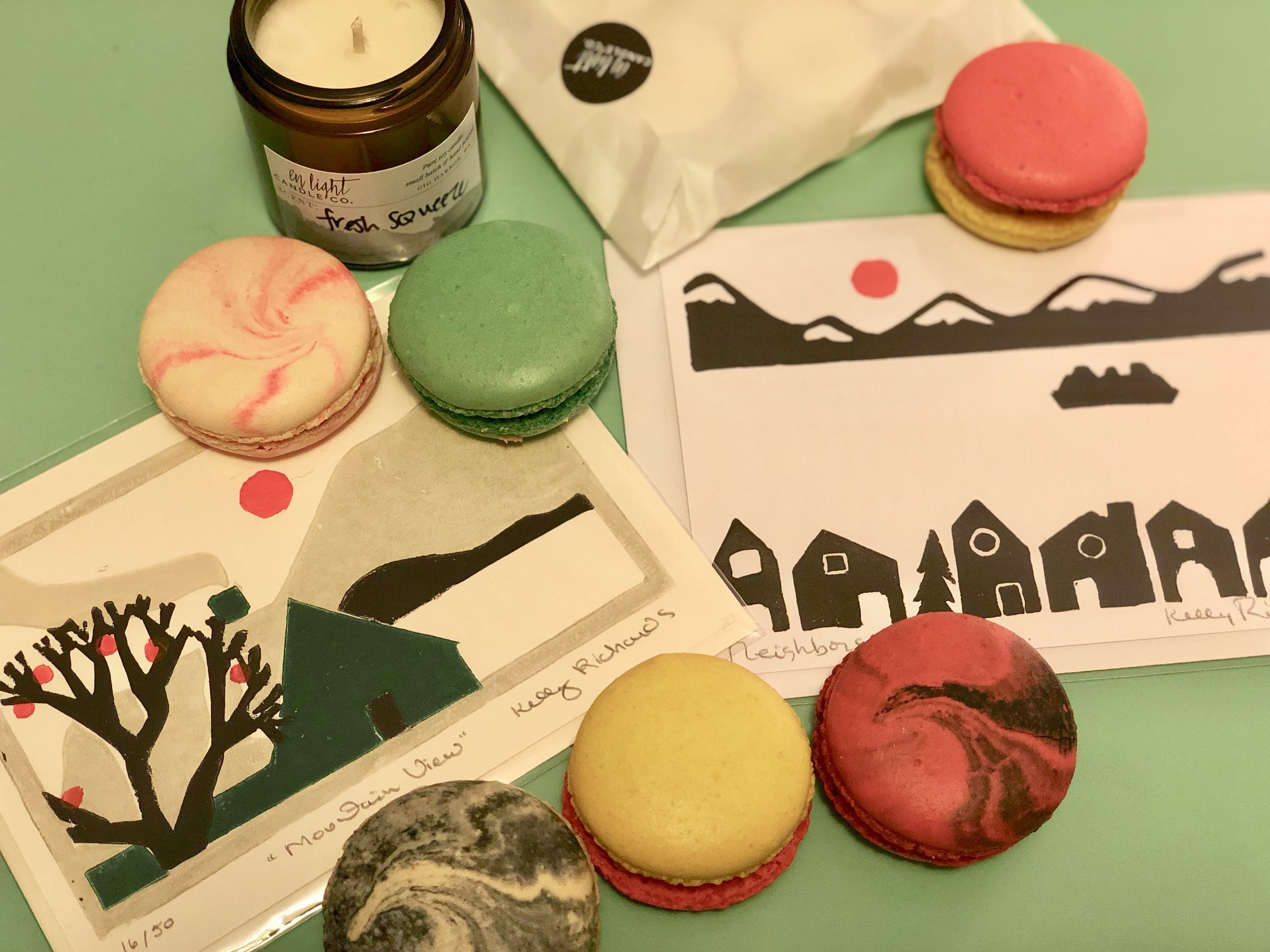 Some beauties from the January Gig Harbor Night Market : delectable macarons from Girl Loves Cake Desserts , block print Tacoma scene cards from Port City Printworks , and a summer-vibes candle from En Light Candle Co. - and there was so much more!