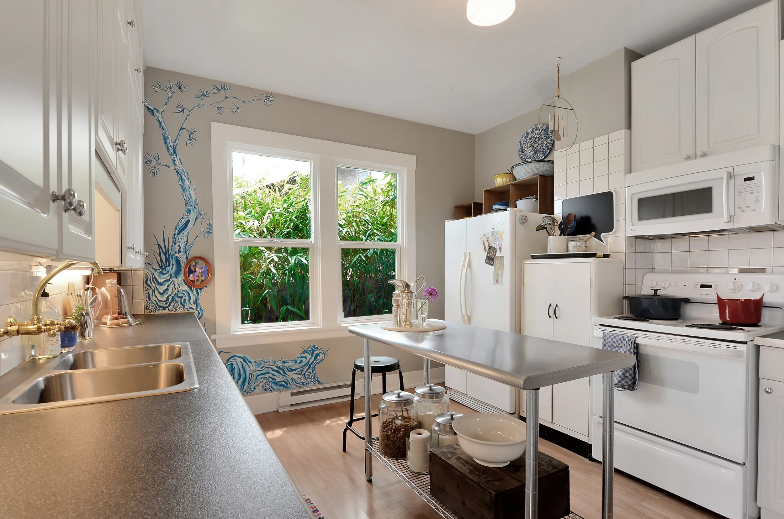Laminate flooring, stainless sink, and a big kitchen window to let in lots of light with bamboo outside to maintain privacy, but still give glimpses of the top of Mt. Rainier.