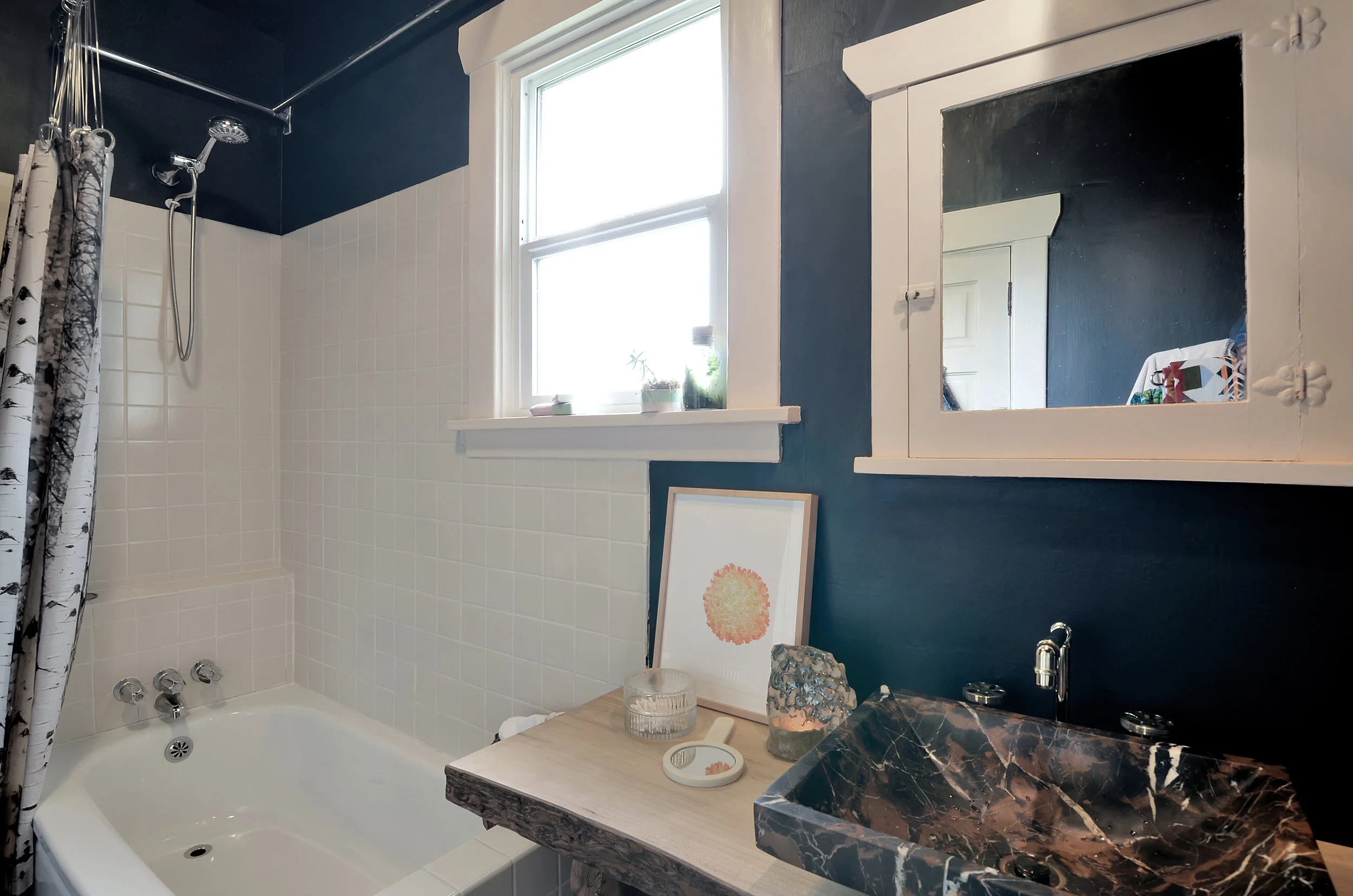 The renovated full bath is located on the main floor and features white tile, refinished fir floors, and a live-edge wooden counter with a stone vessel sink. This isn’t your basic bathroom. It has style that combines rusticity with polish, light and warmth with beautiful moody shadow. As you can tell, we really like it.