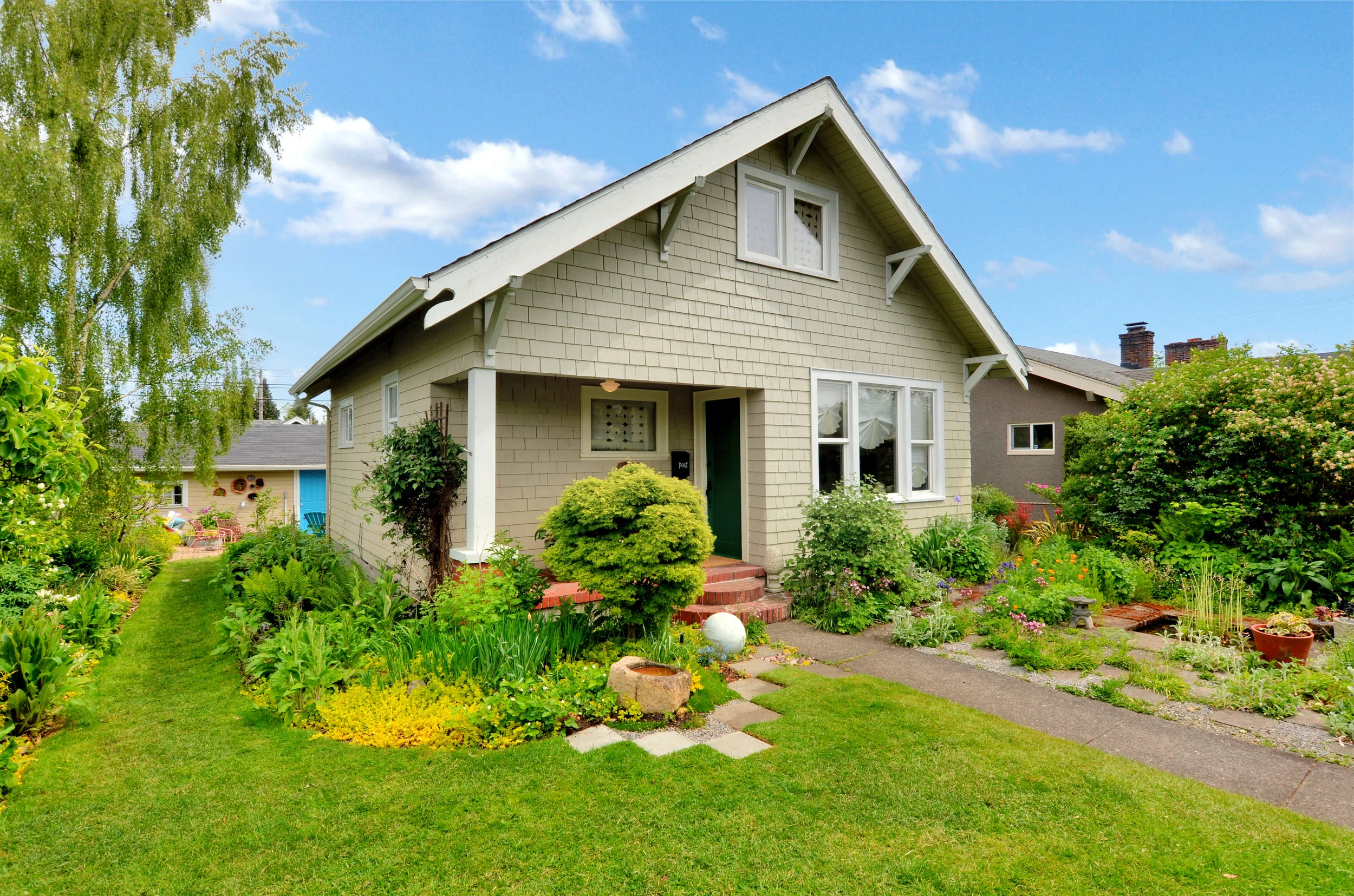 With a privacy hedge, a pond for the birds, paved walkways, a covered front porch, and enclosed back porch, this house with its insulated studio is cozy, comfortable, and calls to all the senses. Listen for birds, smell roses and flowering vines, feel the grass under your bare feet, and enjoy all the colors as the seasons unfold.