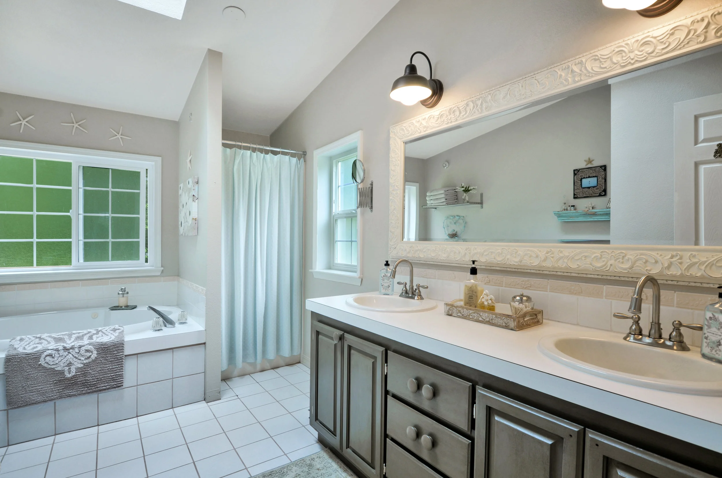 The private full bath includes a tiled-in oval tub with a separate stall shower, skylight, privacy glass in the windows, and a wide vanity with cupboards, drawers, and two sinks so you never have to take turns brushing your teeth.