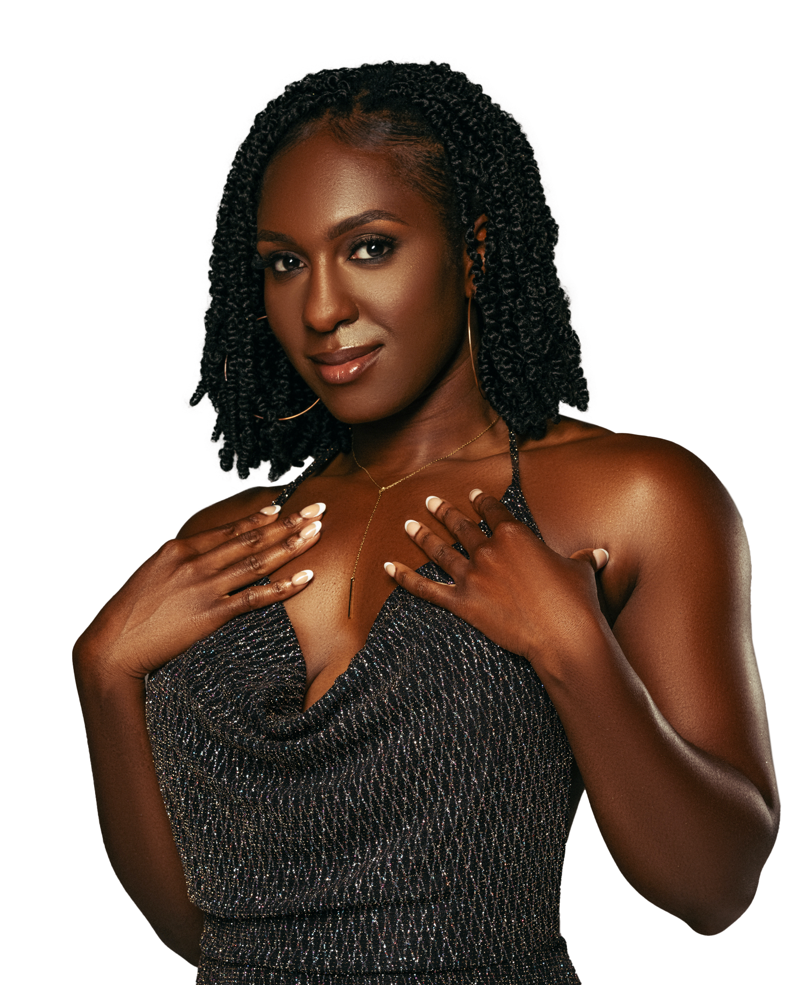 A woman with dark skin and curly black hair, wearing a sparkly dress, gold earring, and a delicate gold necklace, poses with her hands on her chest, looking at the camera.
