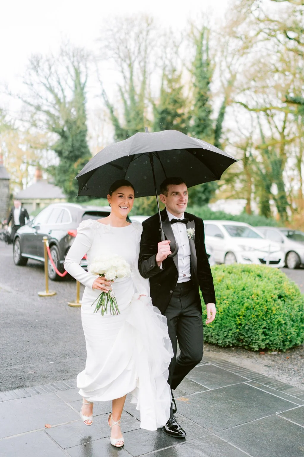 Bride and groom walking to the venue during a rainy wedding day in December