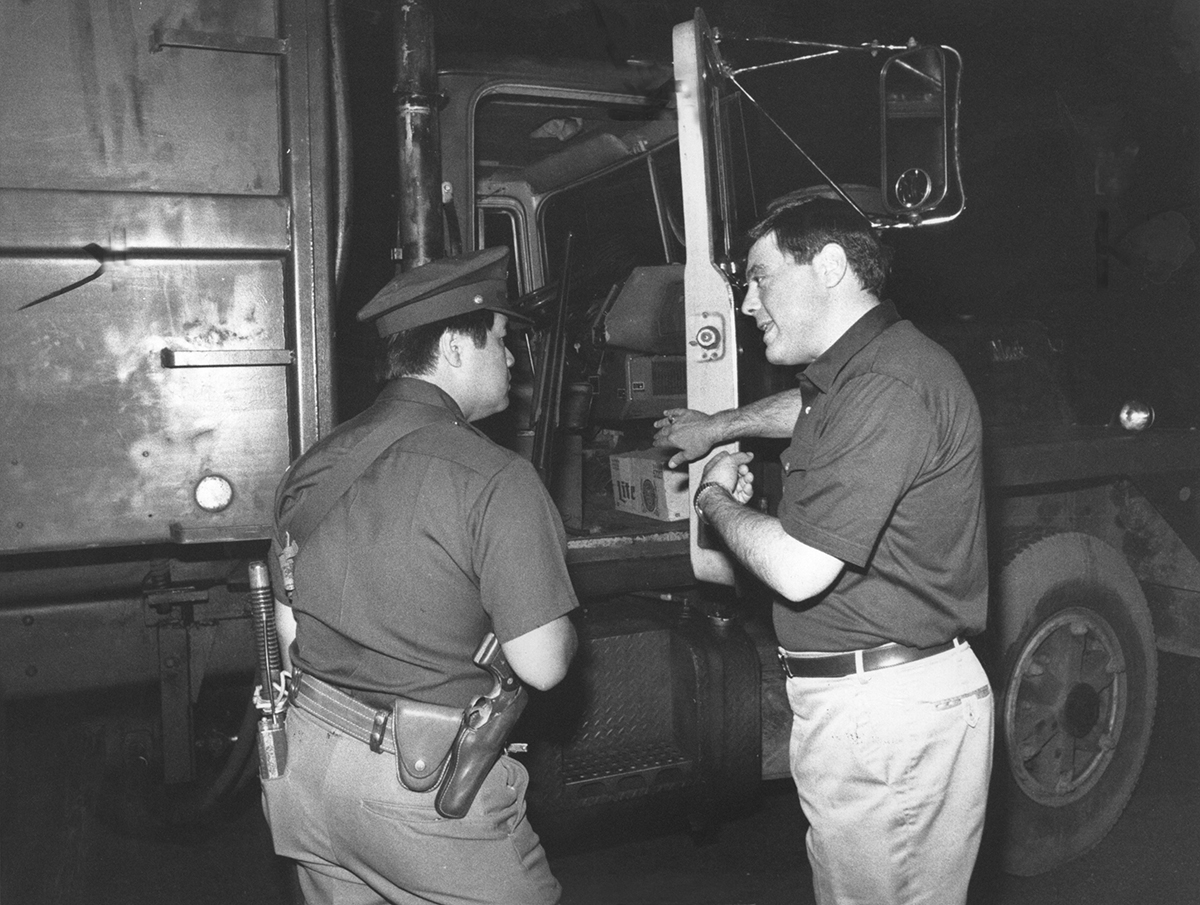 Buddy directs a Providence policeman into the cab of a garbage truck in July 1981. Buddy fired striking garbagemen and hired a private company to drive the trucks, guarded by shotgun-toting police officers. Courtesy of Providence Journal/John L. Hanlon.