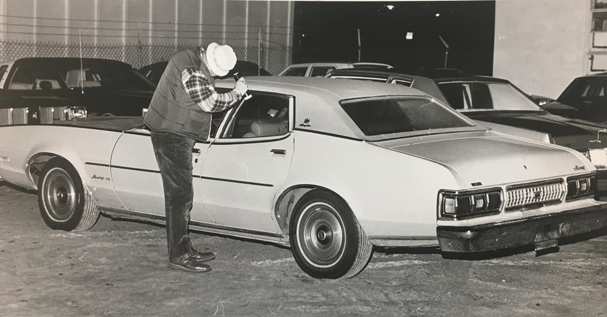 A policeman examines the yellow 1974 Mercury in which George Basmajian's bullet-riddled body was found. Basmajian was sitting in the backseat when he was shot nine times in the torso and face. One detective said the car was steaming up inside when it was discovered. Courtesy of the Providence Journal/William K. Daby .