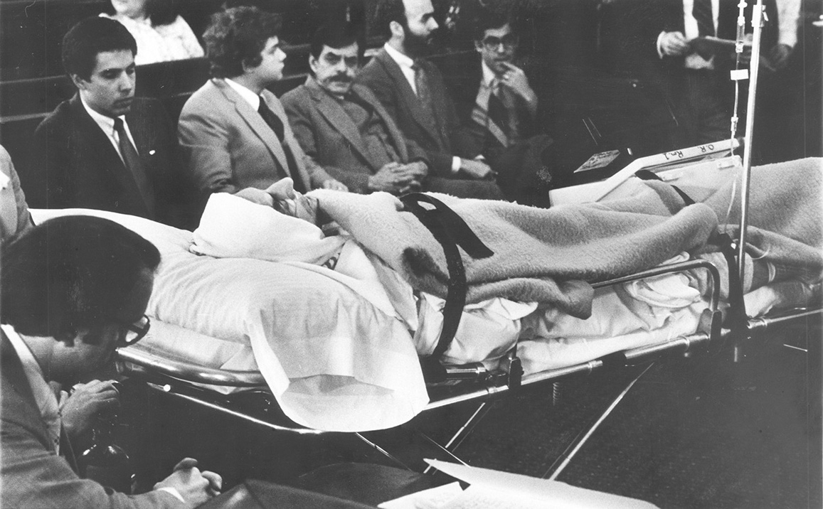 Patriarca, strapped to a stretcher and attached to a portable heart monitor, pleads innocent through his attorney, Cicilline, who said Patriarca's condition was so serious that "he might die at any moment." Courtesy of The Providence Journal.