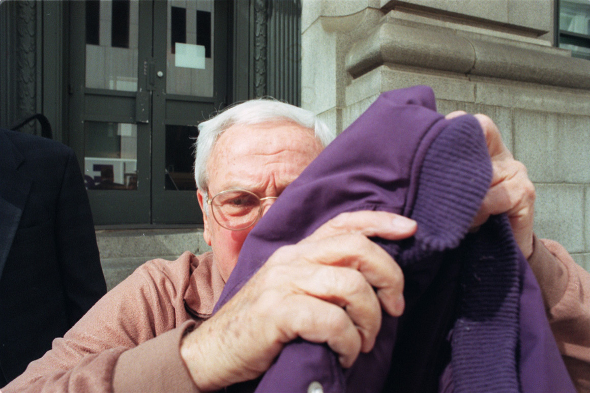 Joe Pannone tries to hide under a coat as he leaves the Federal Court after being indicted on charges of money laundering for bribery. Courtesy of The Providence Journal/Mary Beth Meehan.