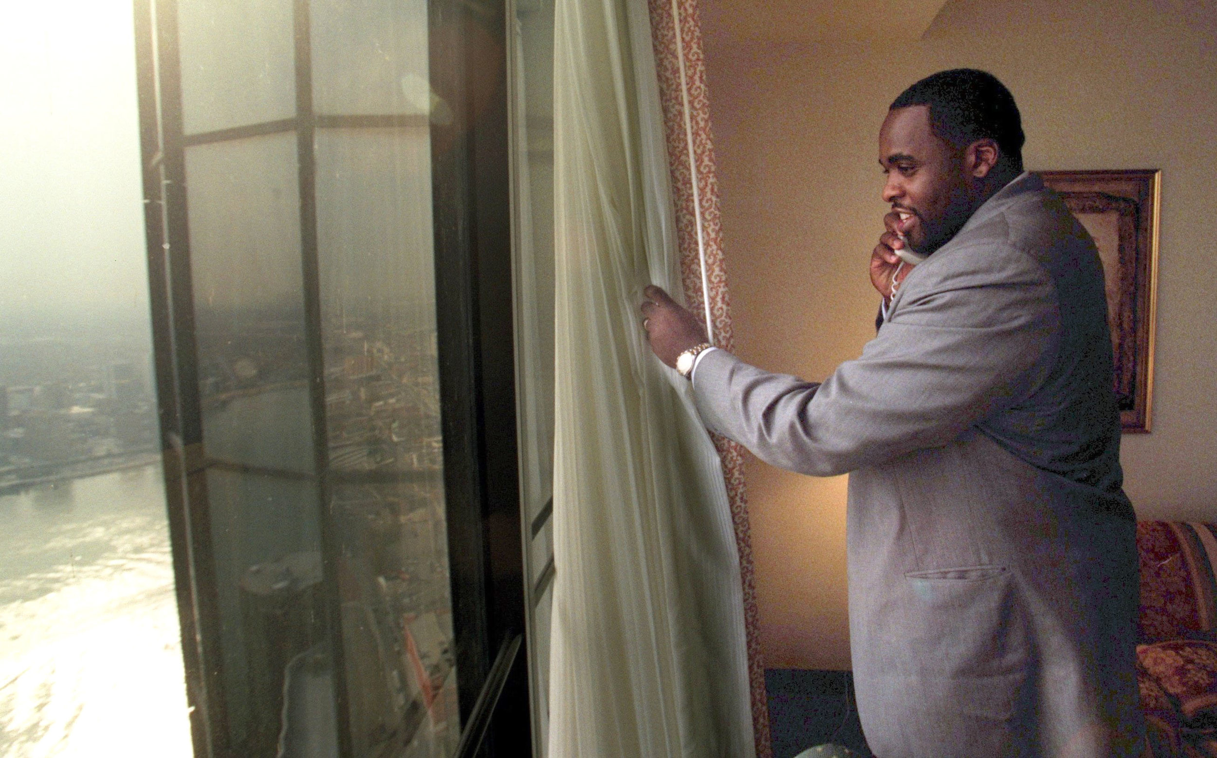 The day after he was elected mayor, Kwame Kilpatrick looks out the window of his 65th-floor suite at the Marriott Renaissance Center while fielding a congratulatory call. Courtesy of the Detroit Free Press.