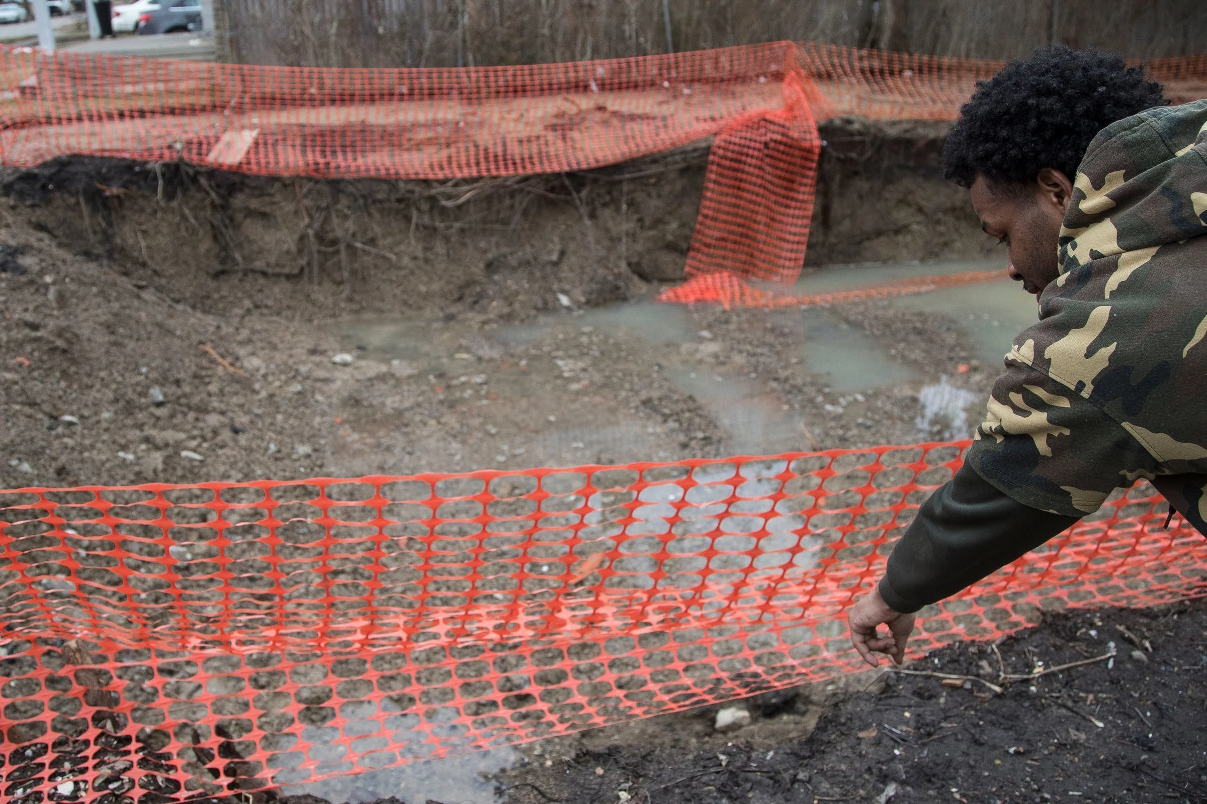 Demolition pits have become a public safety hazard and a symbol of Detroit’s troubled demolition program. Derrick Pratt, a resident on Auburn Street, points out where he slipped into a hole next to his house in February 2019.  Courtesy of the Detroit Free Press.