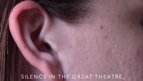 [Image description: screenshot of video by author featuring a cropped image of the profile view of a face and ear. White text overlaying the image says: “Silence in the great theatre,"