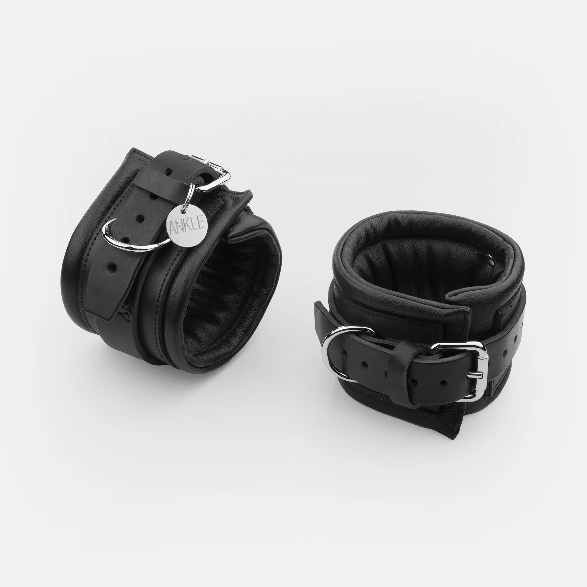 Black padded leather ankle cuffs with adjustable buckles and D-rings by Dominatrix School