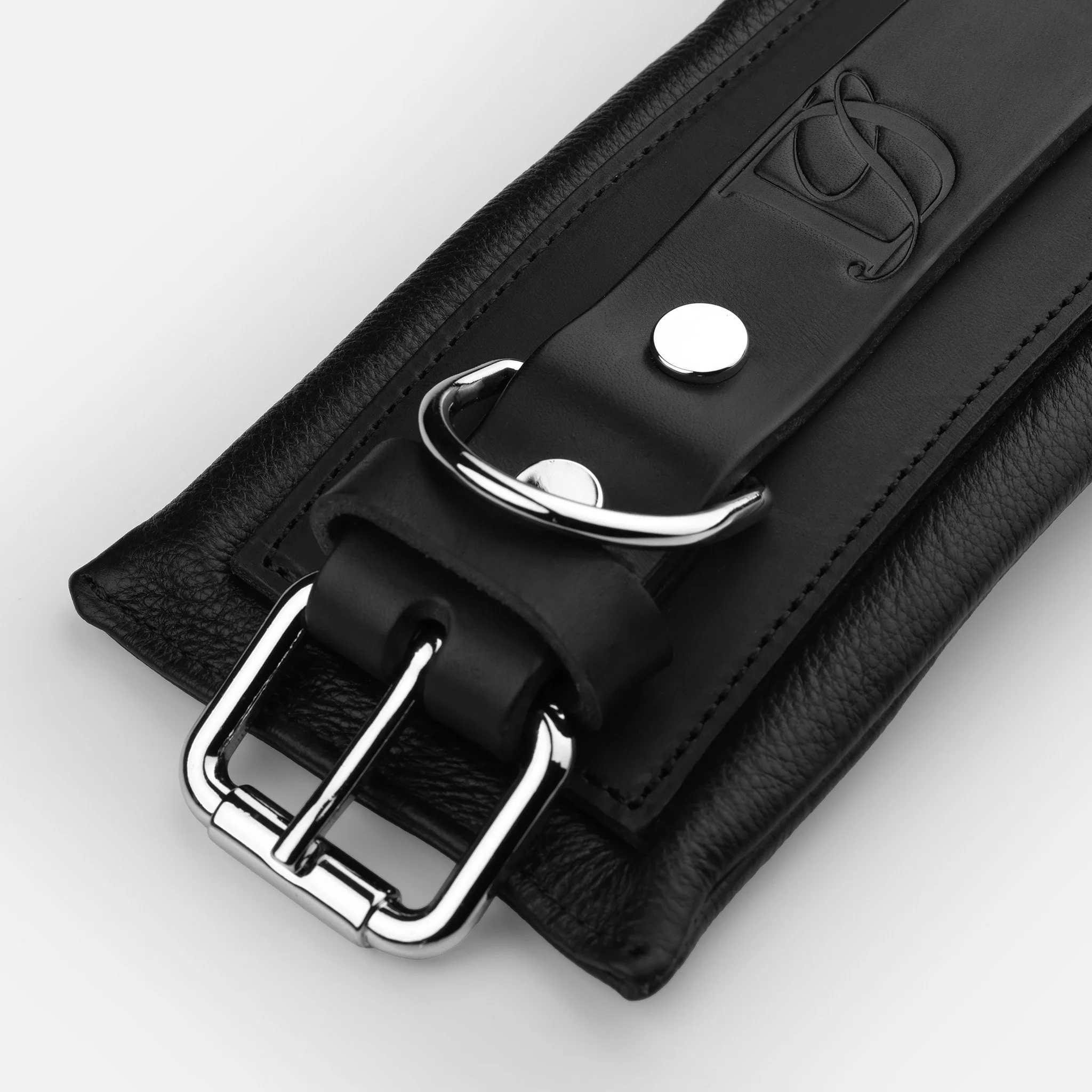 Close-up of stitching and hardware detail on handcrafted black leather anklecuffs