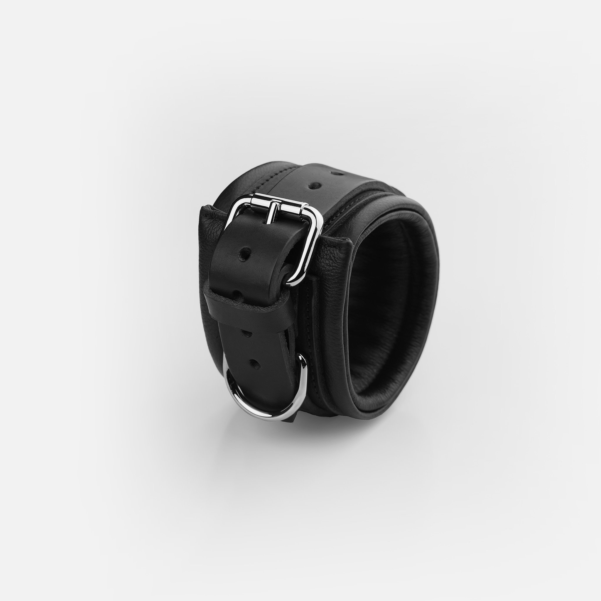 Adjustable roller buckle, multiple holes, and reinforced D-rings on premium black leather wrist cuffs