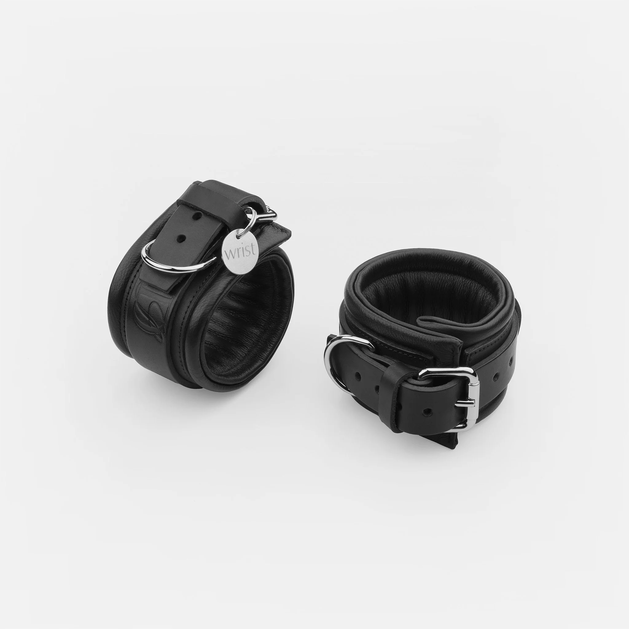 Black padded leather wrist cuffs with adjustable buckles and D-rings by Dominatrix School