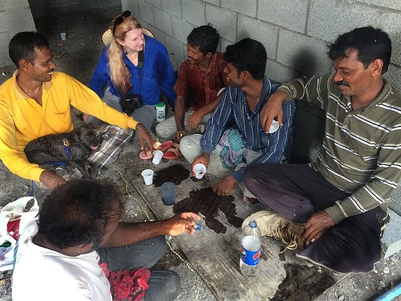 Photojournalist Sherrlyn enjoys hearing a story from Bangladesh workers. See her dog in the man's lap?