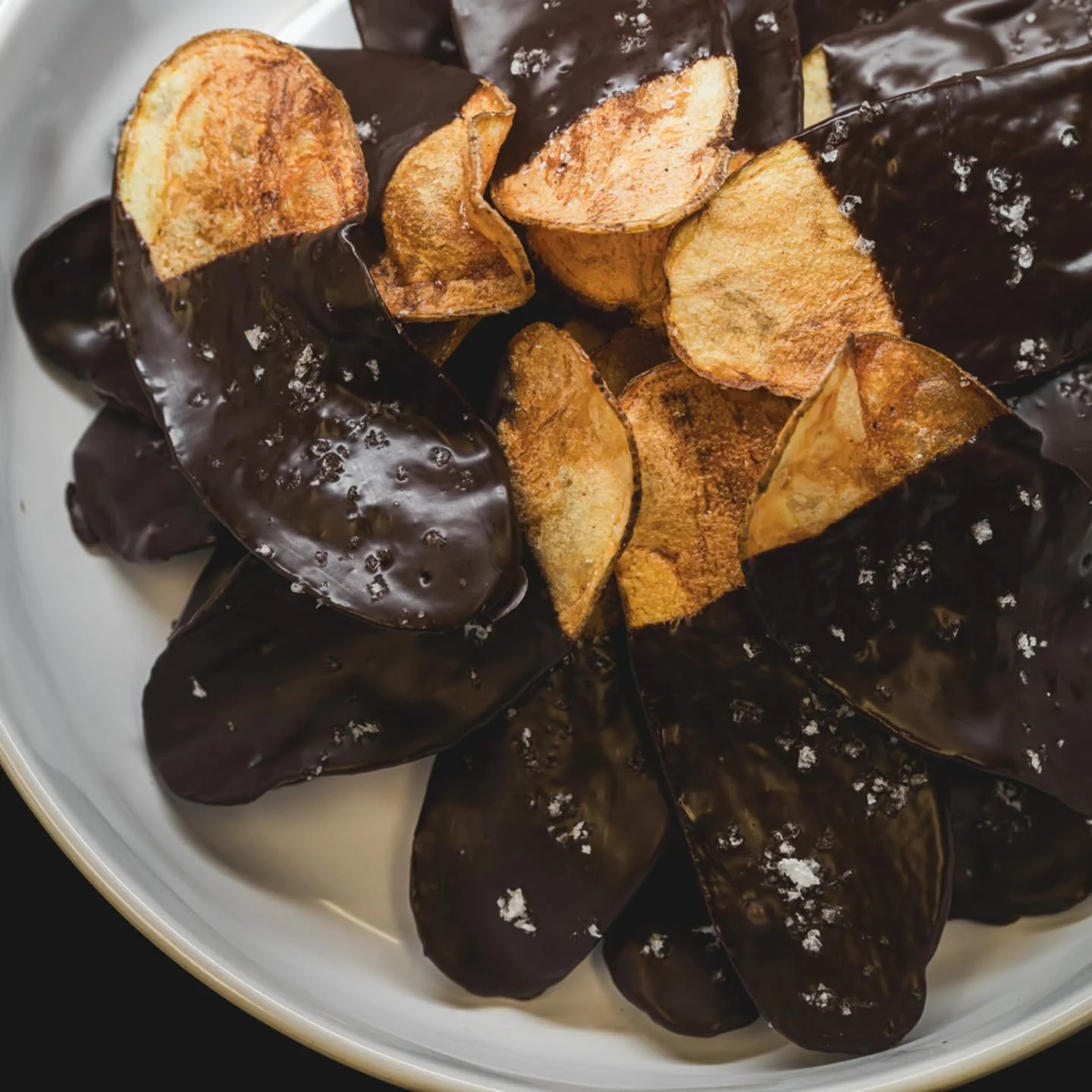 An after dinner sweet that's a little salty, too. Russet potatoes hand sliced, fried, and dipped into melted dark chocolate topped with maldon salt.

📸: @thederekphoto