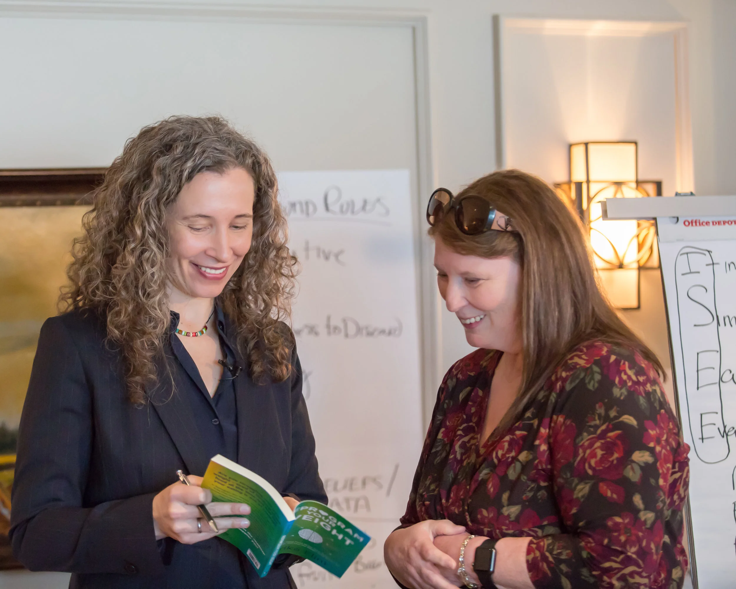 Erika Flint signing a copy of her best-selling book Reprogram Your Weight at a live event for clients.