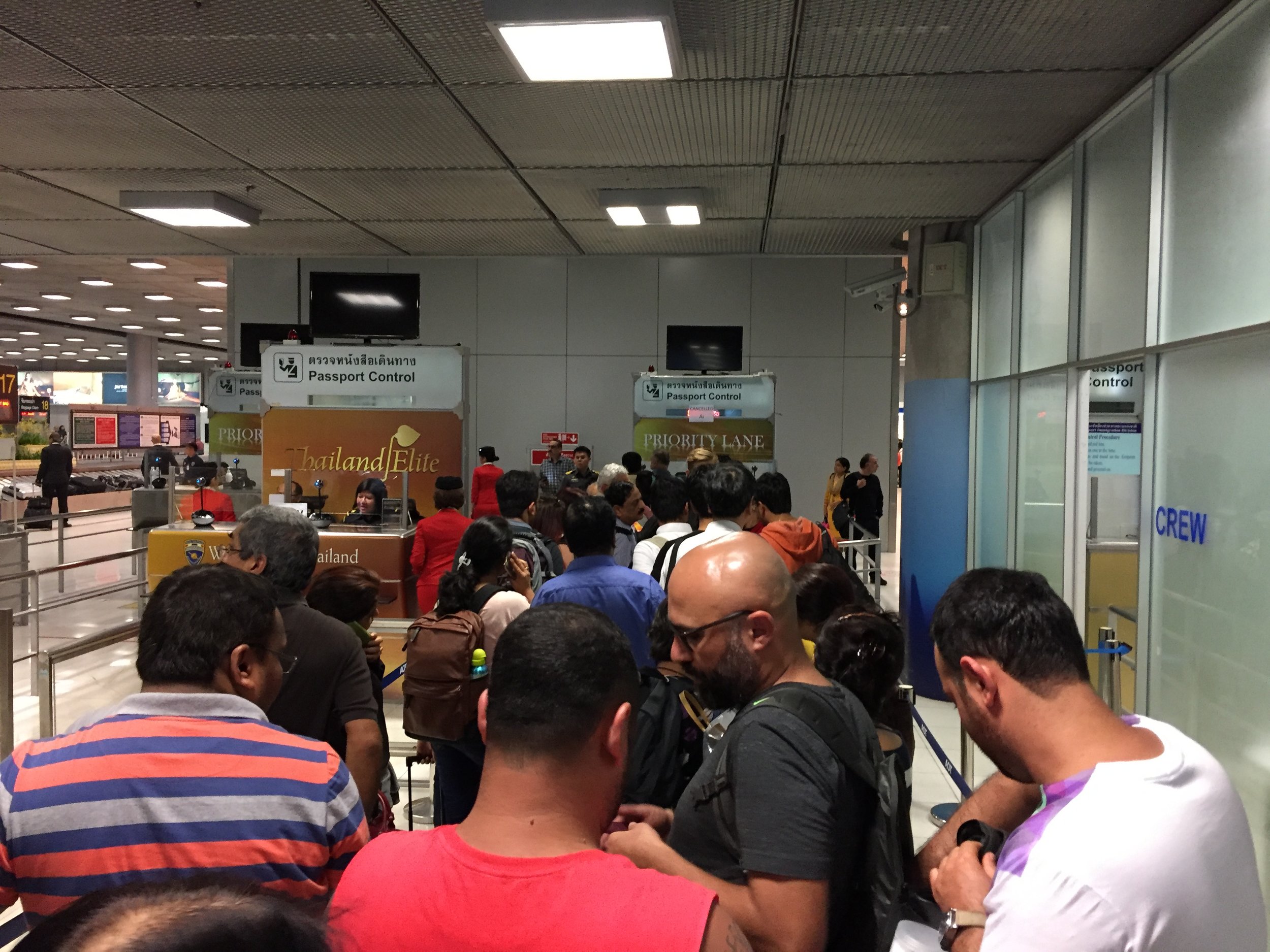 Irate travelers wait in the immigration line to be re-accepted for entry to Thailand and shuttled to a hotel.