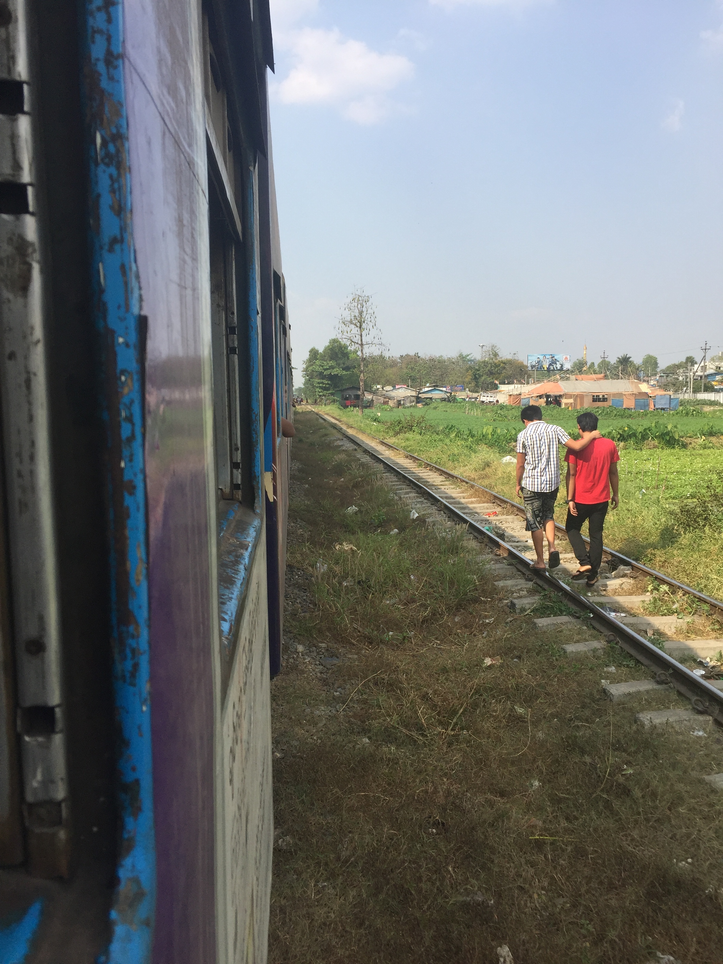 Two friends walk along the circle railroad tracks in Yangon.