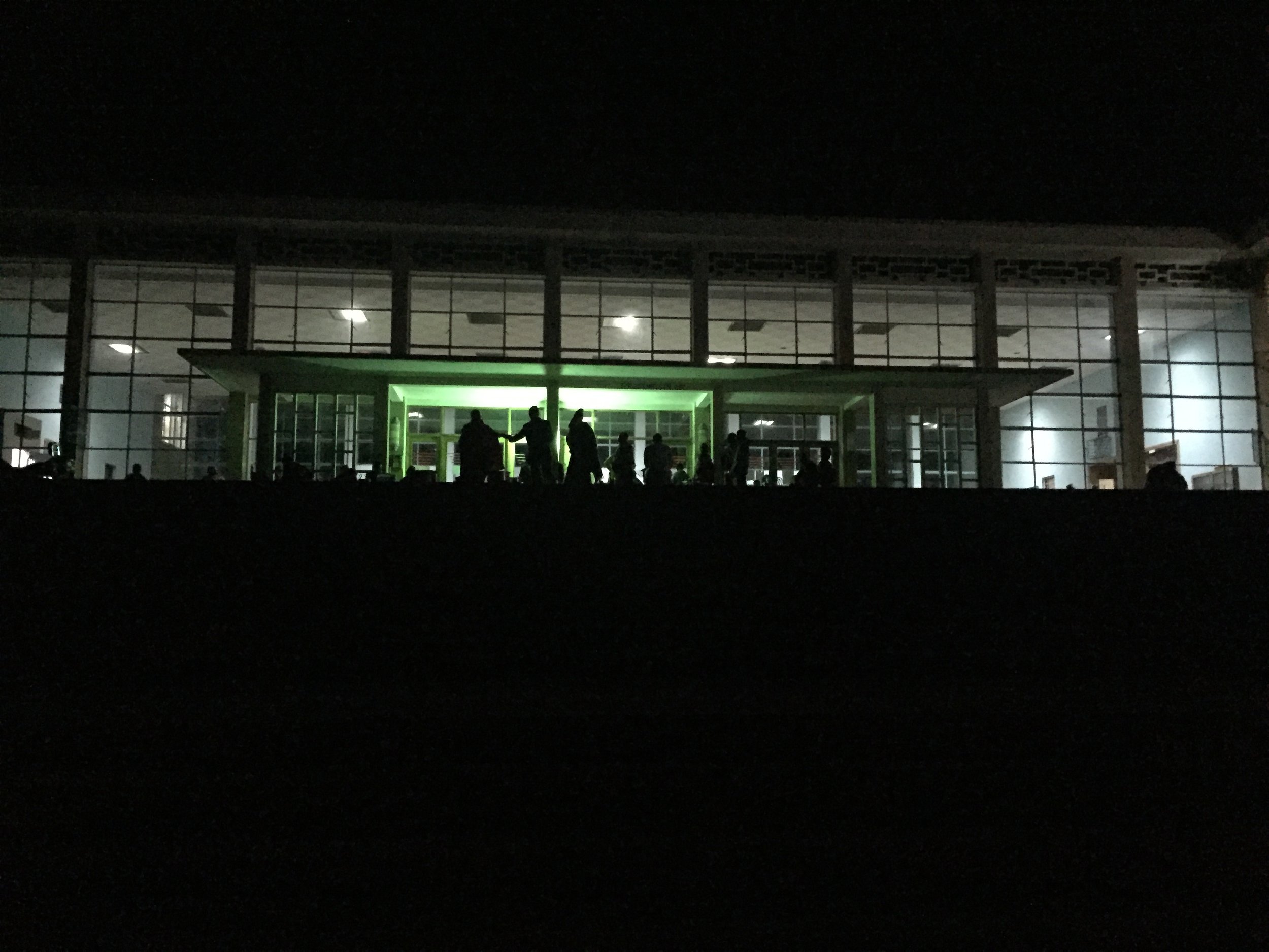 The Mbeya railway station by night, barely lit, with vendors selling chipsy - fried eggs made with french fries and ketchup - outside.