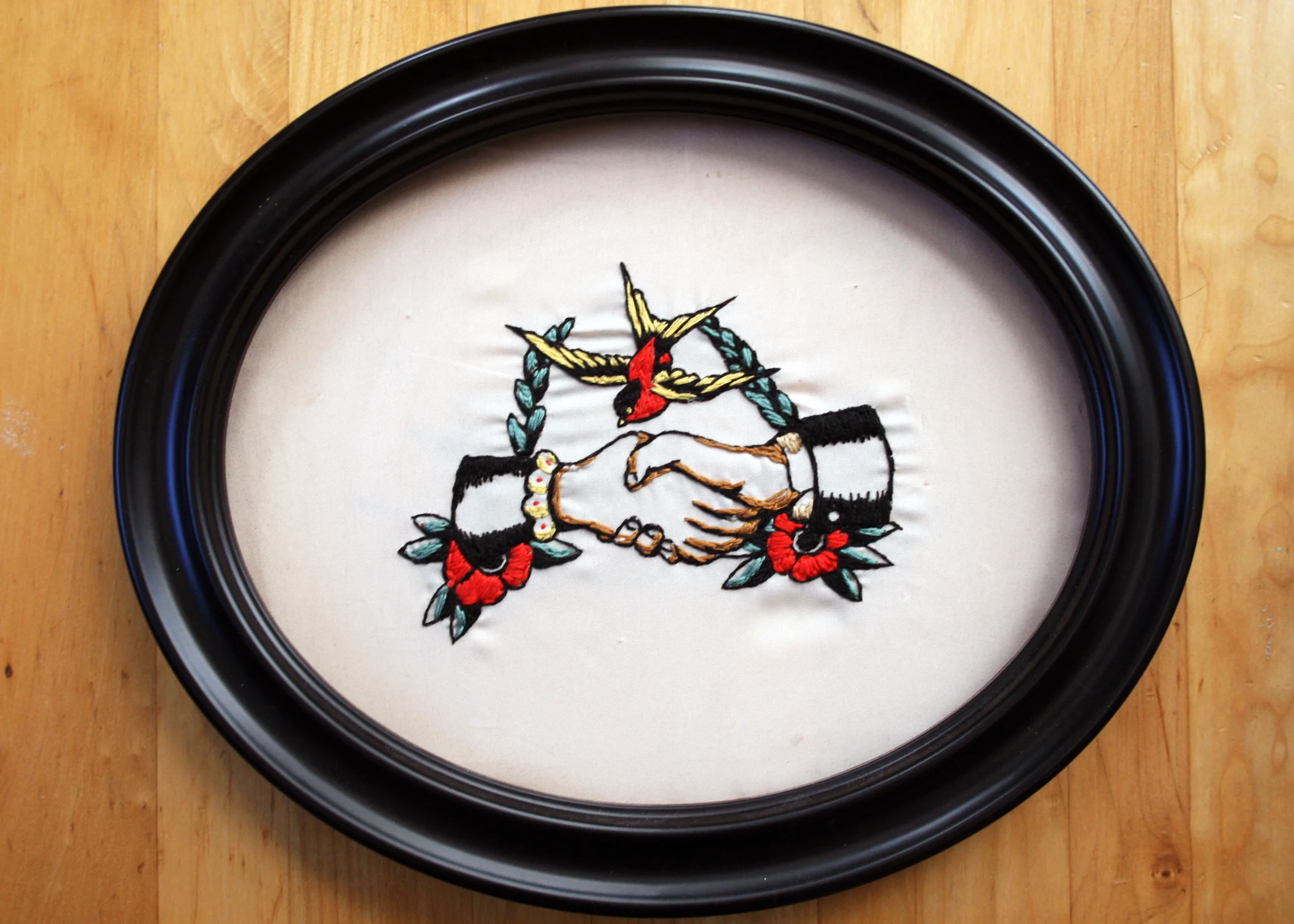 Traditional Hands & Swallow, 10in x 8in oval, fabric stretched on wooden frame, embroidery floss.