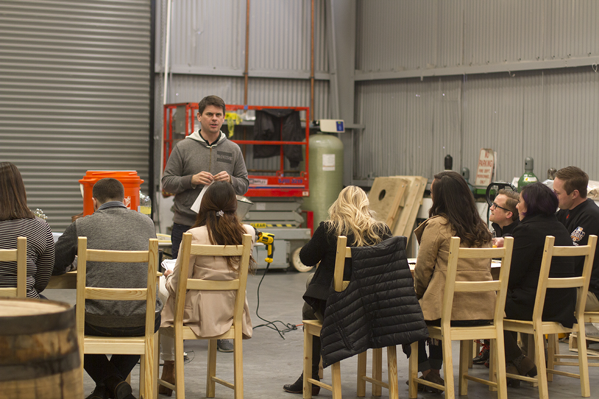 Man gives home brew class in brewery warehouse.