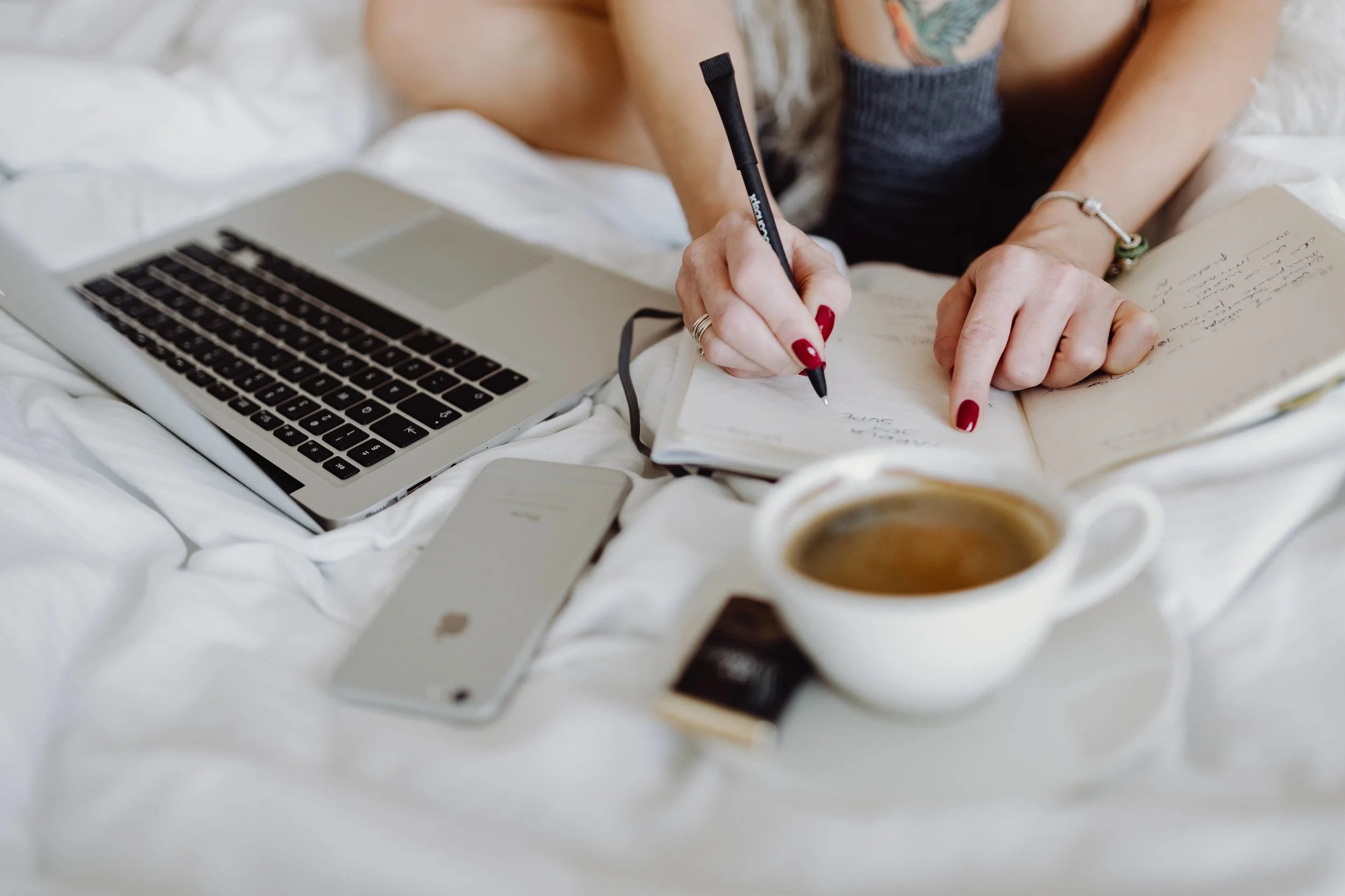 kaboompics_Woman working on a laptop while enjoying a breakfast coffee and chocolate in bed.jpg