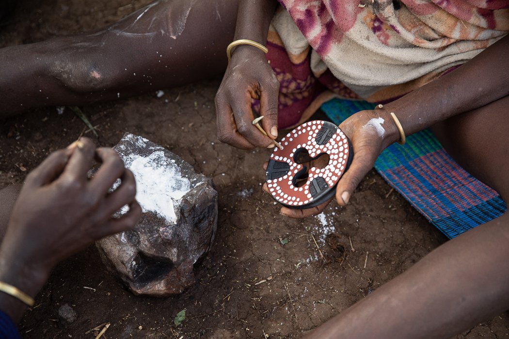 painting making lip plates in mursi tribe village Ethiopia